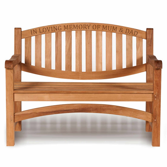 a wooden memorial bench with carved text along the top rail saying in loving memory of mum & dad