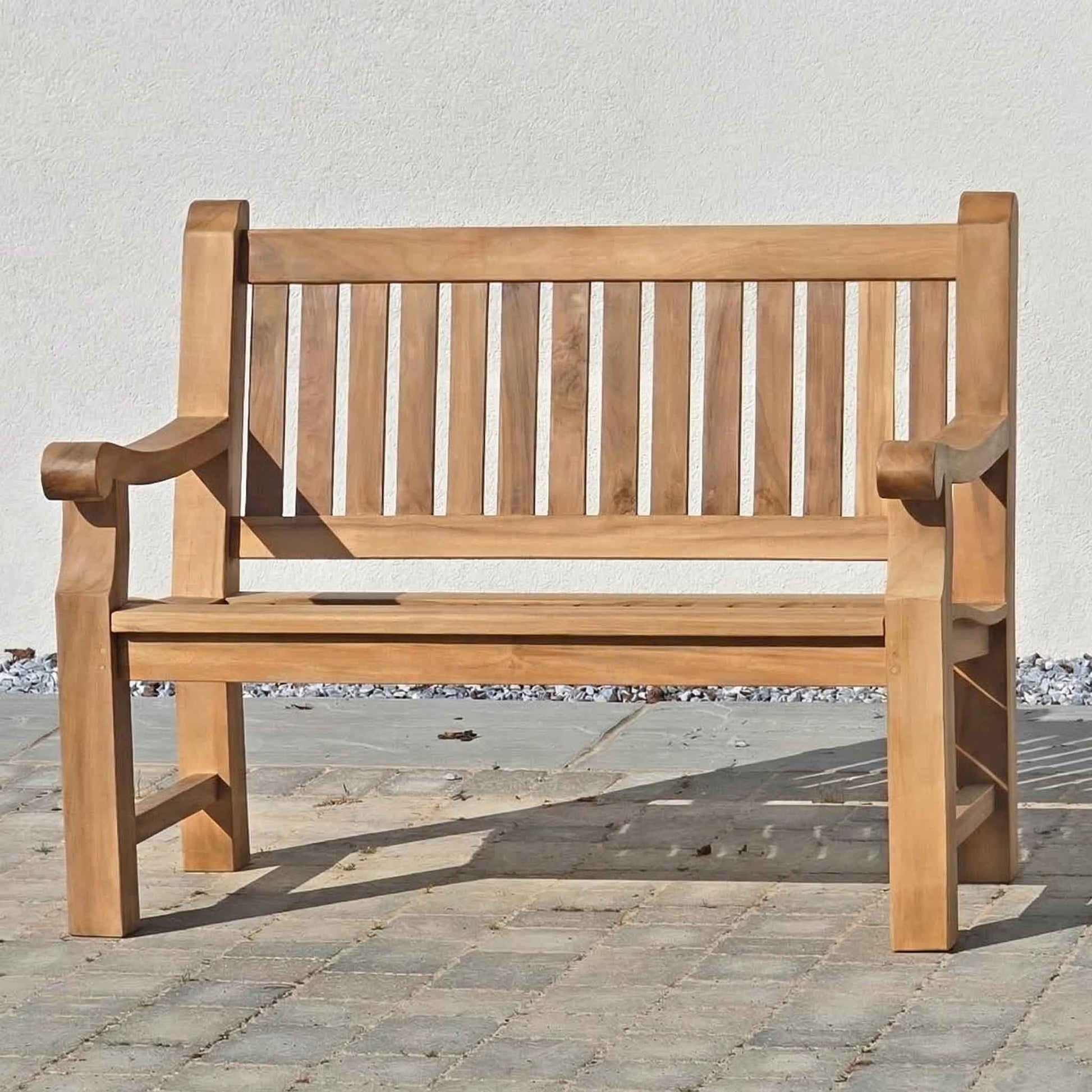 FSC 2 seat Wooden memorial garden bench on a stone patio with a white wall background
