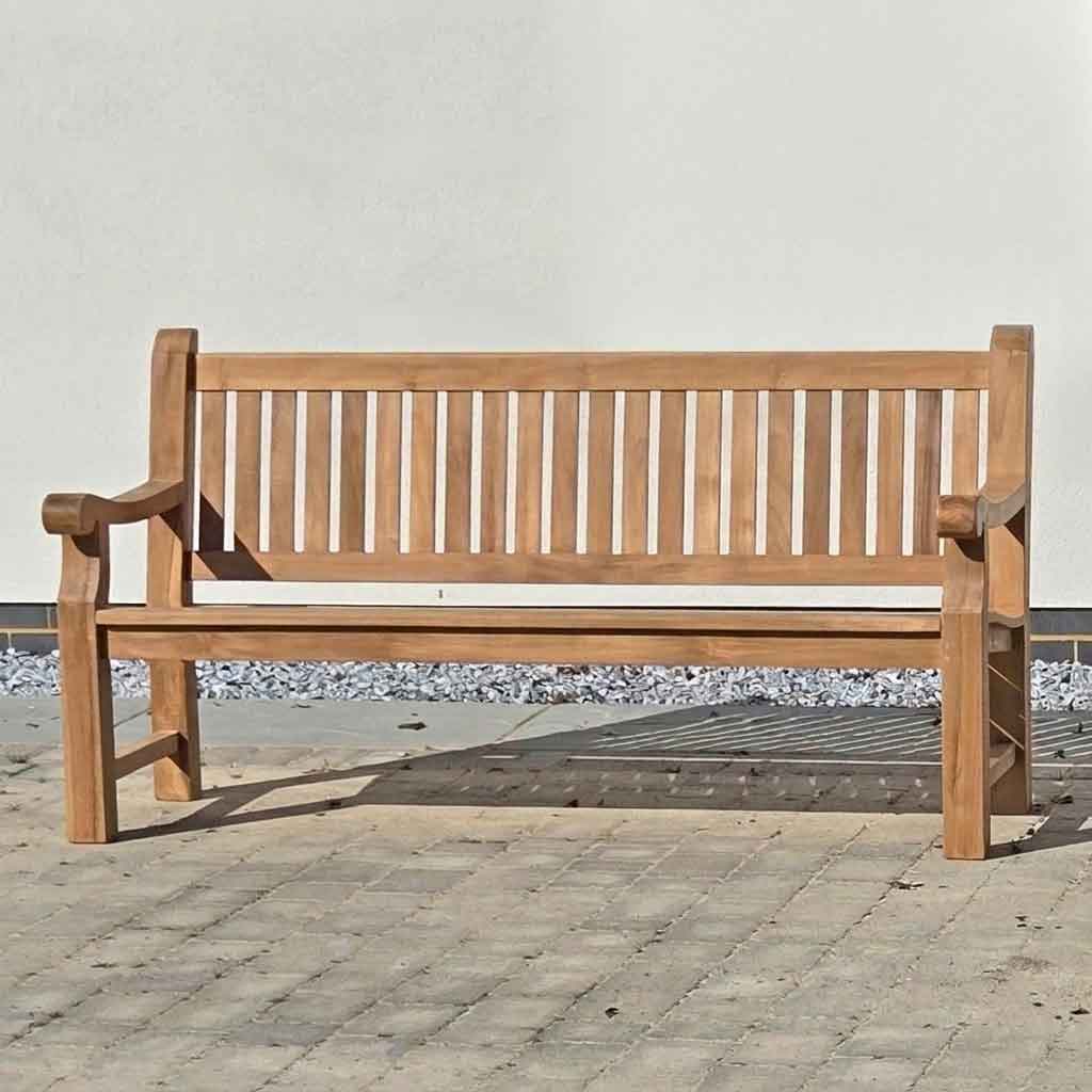 FSC 4 seat Wooden memorial garden bench on a stone patio with a white wall background