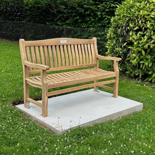 Wooden memorial bench fixed to a concrete plinth in a rural setting