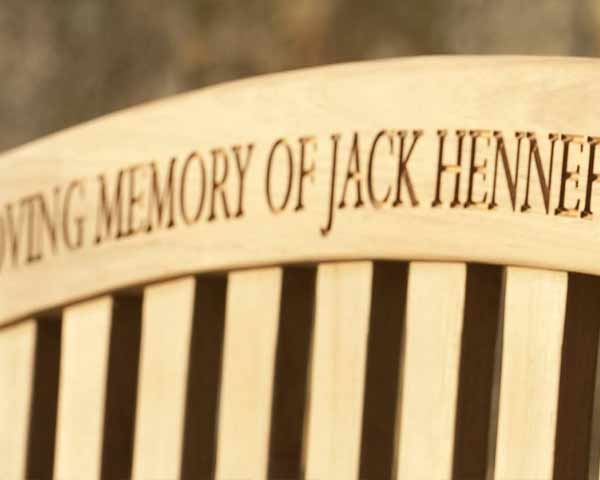 Memorial bench with engraved text 'In Loving Memory of Jack' on a blurred background