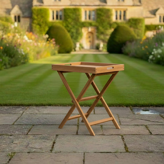 Wooden teak folding tray and stand on a patio with a garden and house in the background
