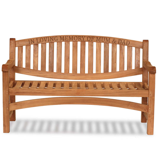 a wooden memorial bench with carved text along the top rail saying in loving memory of mum & dad