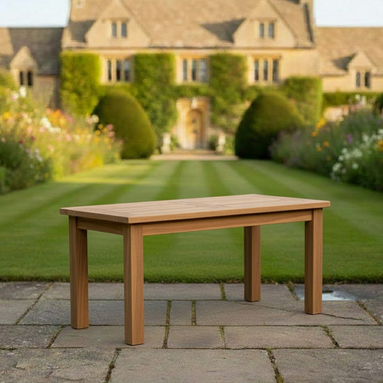 Wooden rectangular garden teak coffee table in a well-maintained garden with a house in the background