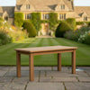 Wooden rectangular garden teak coffee table in a well-maintained garden with a house in the background