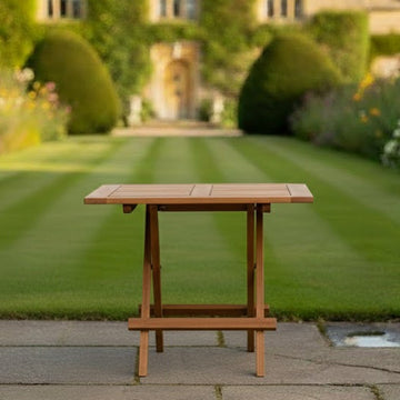 Wooden square folding garden coffee table on a patio with a blurred garden and building in the background