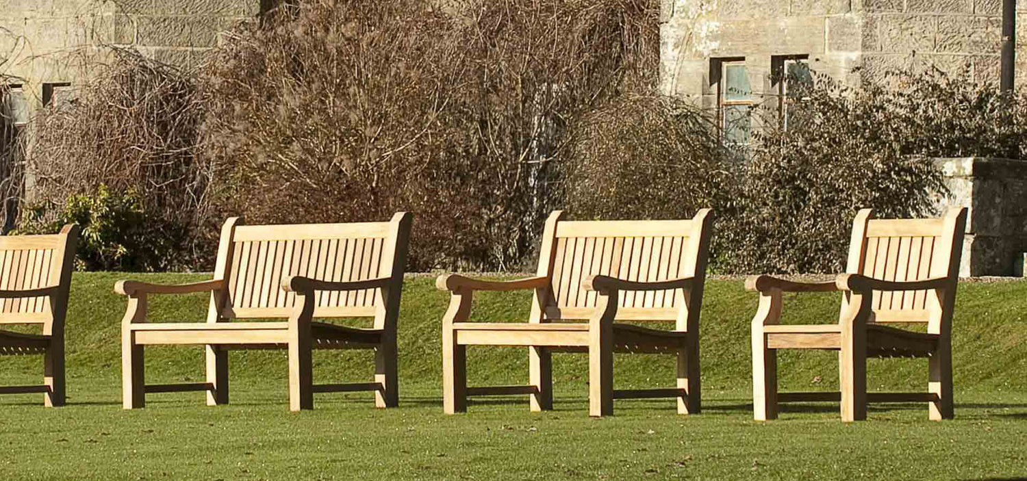 A row of wooden memorial benches on a lawn in front of a castle in England